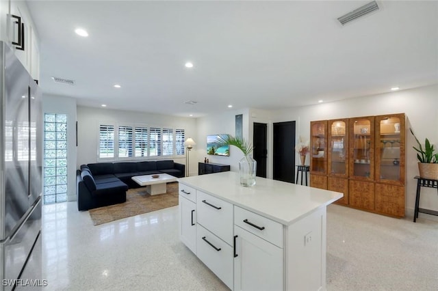 kitchen featuring white cabinets, a kitchen island, visible vents, and stainless steel fridge