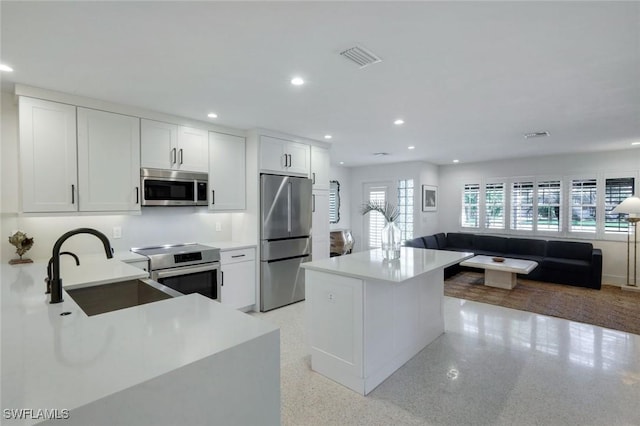 kitchen featuring a sink, open floor plan, light countertops, appliances with stainless steel finishes, and recessed lighting