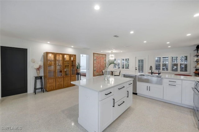 kitchen featuring stainless steel dishwasher, a center island, a sink, light countertops, and recessed lighting