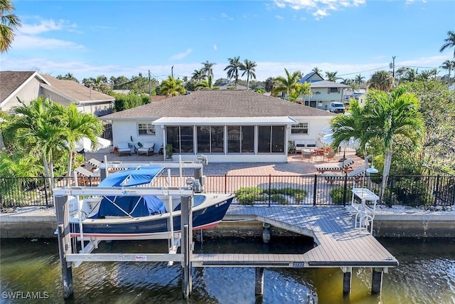 dock area with a patio area, a water view, fence, and boat lift