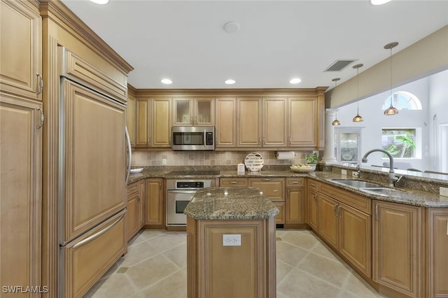 kitchen featuring visible vents, appliances with stainless steel finishes, a sink, a kitchen island, and dark stone countertops