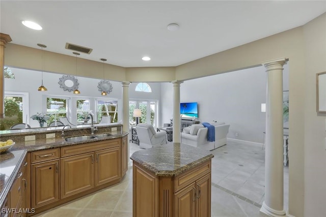 kitchen with visible vents, brown cabinetry, a sink, dark stone countertops, and ornate columns