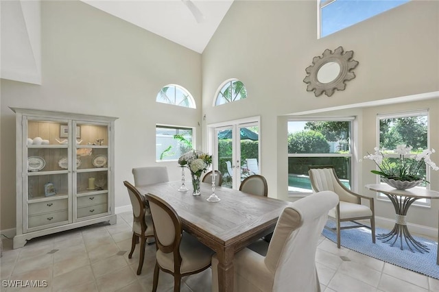 dining area with light tile patterned floors, high vaulted ceiling, french doors, and baseboards