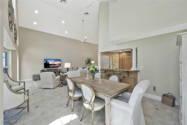 dining space featuring light tile patterned floors, a high ceiling, visible vents, baseboards, and ornate columns