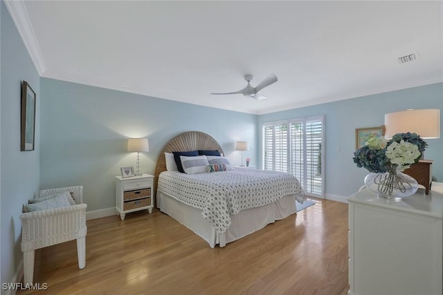 bedroom featuring baseboards, wood finished floors, visible vents, and crown molding