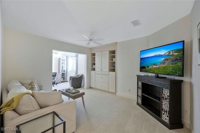 living room featuring light carpet, baseboards, visible vents, a ceiling fan, and a glass covered fireplace