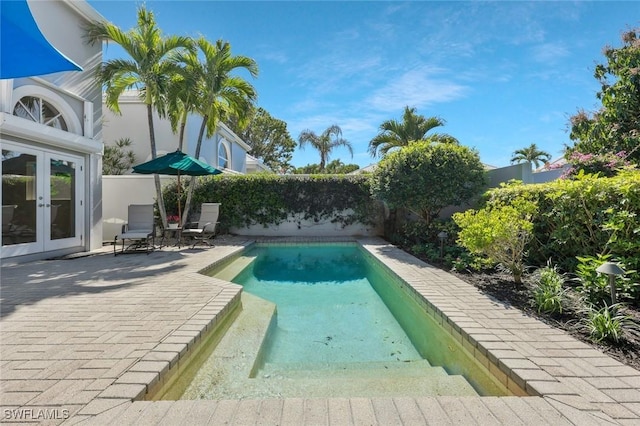 view of swimming pool featuring a patio, french doors, a fenced backyard, and a fenced in pool