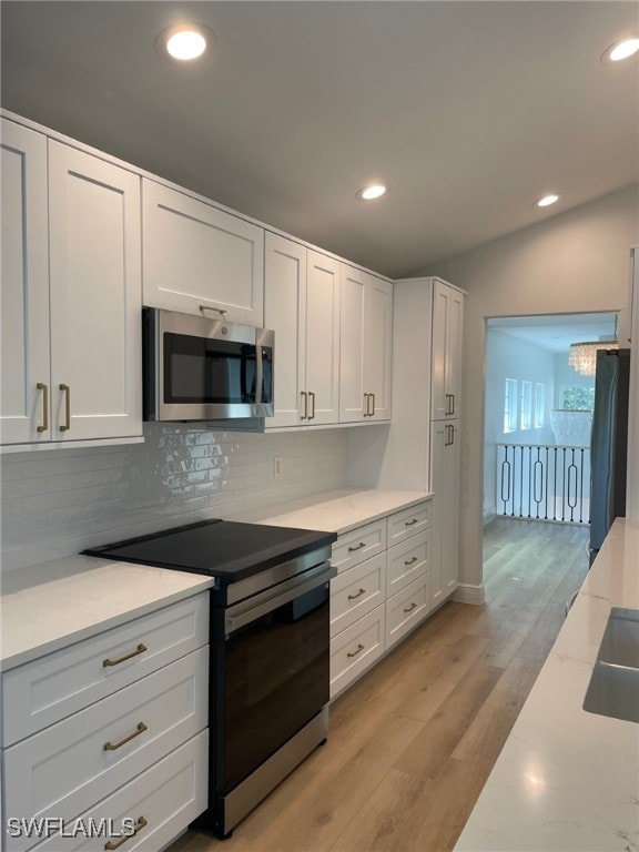 kitchen featuring stainless steel appliances, light wood-type flooring, white cabinetry, and backsplash