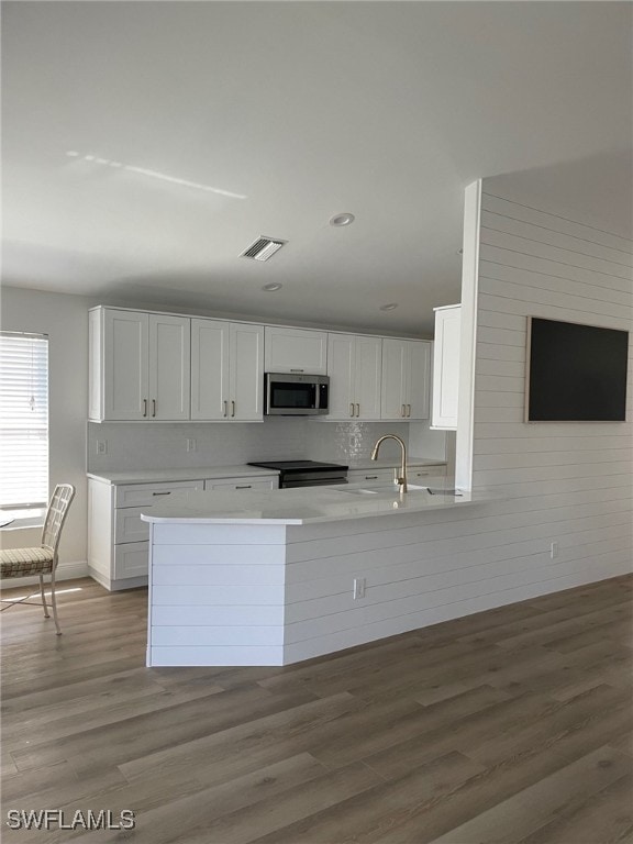 kitchen with visible vents, white cabinets, stainless steel microwave, light countertops, and a sink