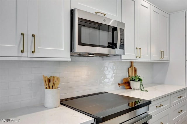 kitchen featuring white cabinetry, decorative backsplash, light stone countertops, and appliances with stainless steel finishes