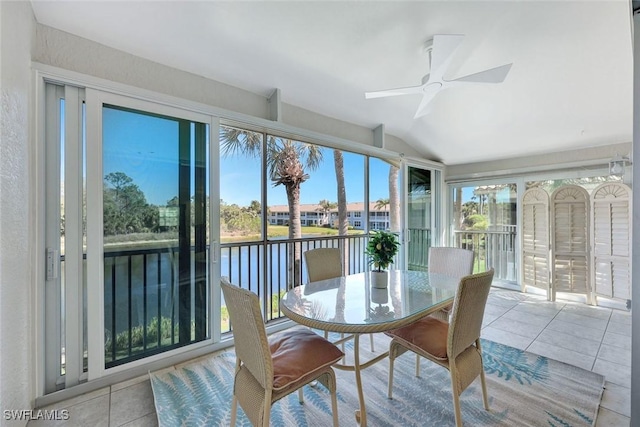 sunroom / solarium featuring vaulted ceiling, a ceiling fan, a water view, and a wealth of natural light