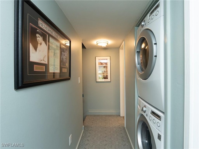 clothes washing area featuring stacked washer and dryer, laundry area, and baseboards