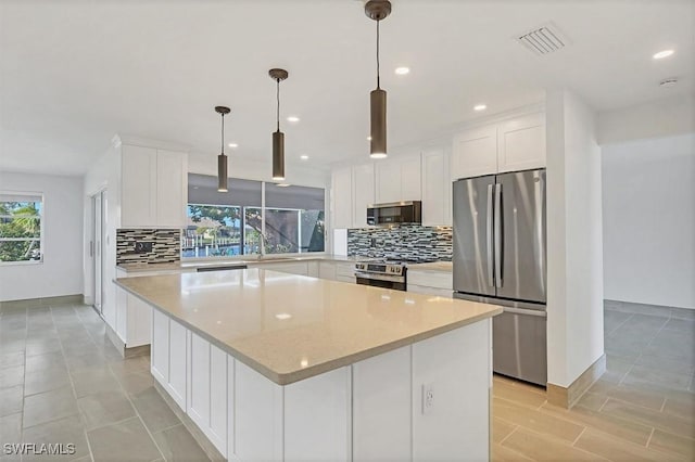 2501 Rio Grande Dr, Punta Gorda, FL 33950 - kitchen featuring visible vents, a center island, decorative backsplash, appliances with stainless steel finishes, and white cabinets