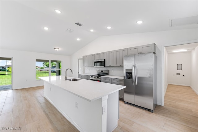 kitchen with stainless steel appliances, light countertops, gray cabinetry, a kitchen island with sink, and a sink