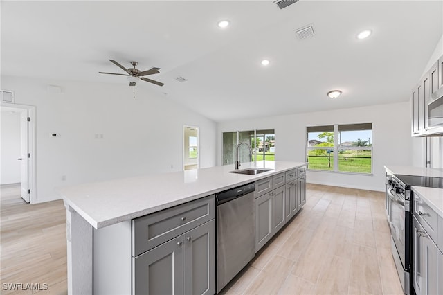 kitchen with light countertops, appliances with stainless steel finishes, a sink, and gray cabinetry