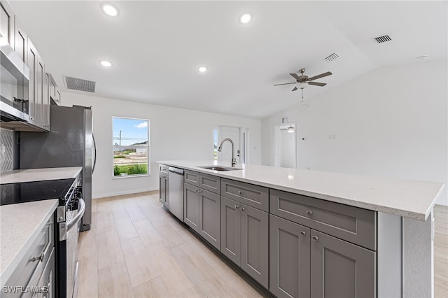 kitchen with lofted ceiling, gray cabinets, visible vents, appliances with stainless steel finishes, and a sink