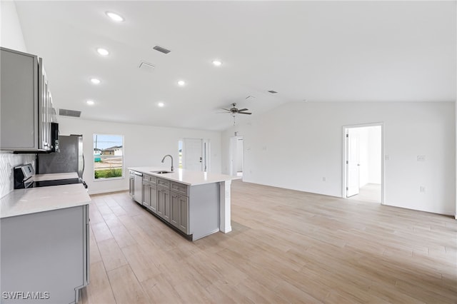 kitchen with lofted ceiling, light countertops, a sink, and gray cabinetry