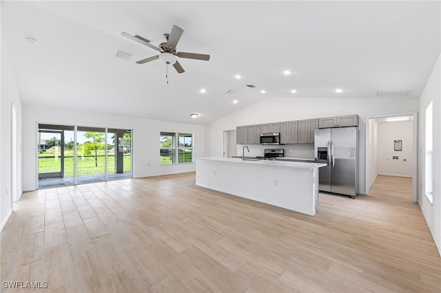 kitchen with a kitchen island with sink, stainless steel appliances, open floor plan, light countertops, and gray cabinets