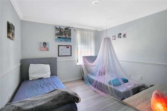 bedroom featuring ornamental molding, wood finished floors, and baseboards