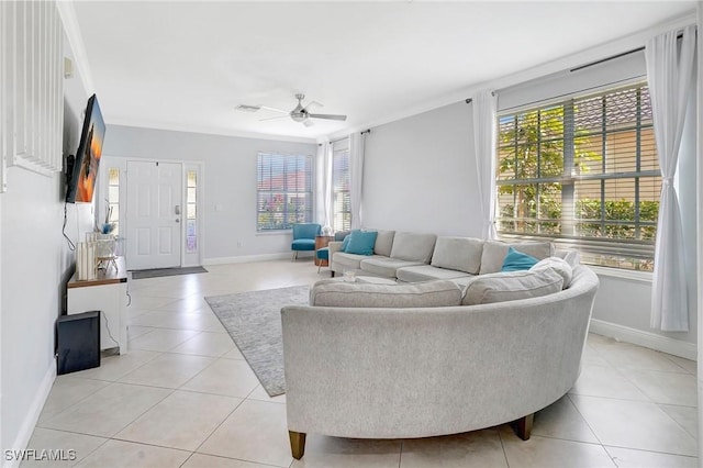 living area featuring a ceiling fan, light tile patterned flooring, crown molding, and baseboards