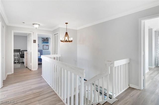 hall featuring crown molding, light wood-type flooring, an upstairs landing, and an inviting chandelier