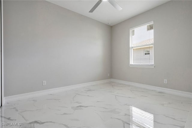 unfurnished room with marble finish floor, ceiling fan, and baseboards