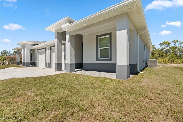 exterior space featuring concrete driveway, an attached garage, a yard, central air condition unit, and stucco siding