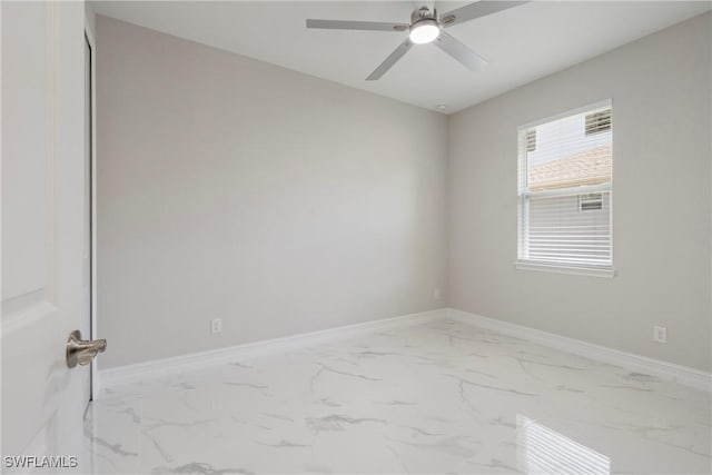 unfurnished room featuring marble finish floor, ceiling fan, and baseboards