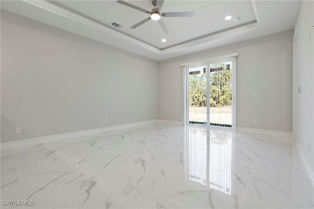 empty room with marble finish floor, visible vents, and a raised ceiling