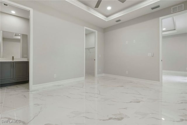 unfurnished bedroom featuring visible vents, marble finish floor, a closet, a tray ceiling, and a walk in closet