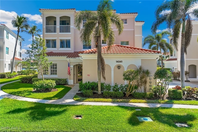 view of front of house featuring a front yard, a tile roof, and stucco siding