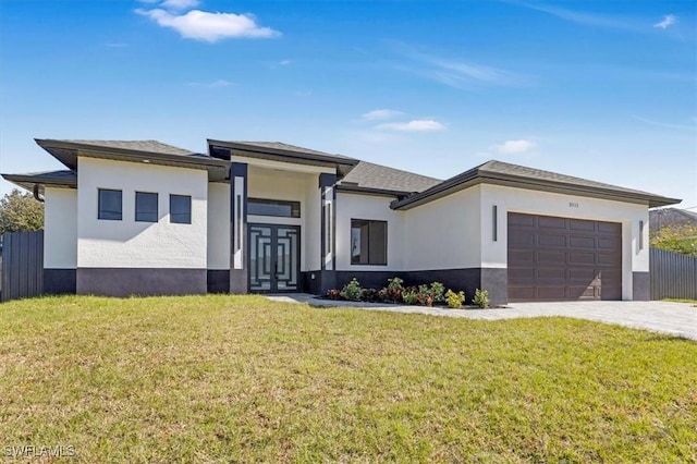 prairie-style house featuring a garage, a front yard, fence, and stucco siding