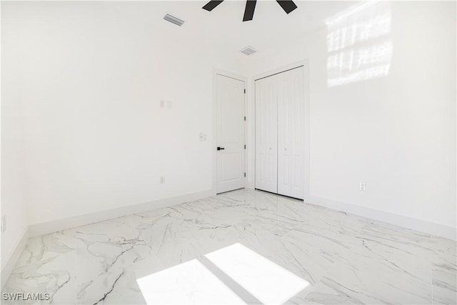 empty room featuring ceiling fan, marble finish floor, visible vents, and baseboards