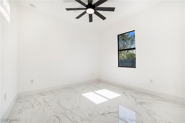 spare room with marble finish floor, ceiling fan, and baseboards