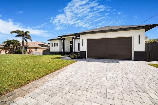 view of front of property with an attached garage, fence, decorative driveway, stucco siding, and a front yard