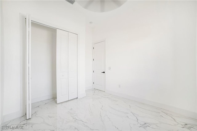 unfurnished bedroom featuring marble finish floor, a closet, and baseboards