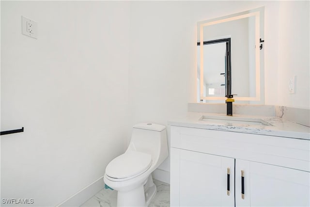 bathroom featuring toilet, marble finish floor, vanity, and baseboards