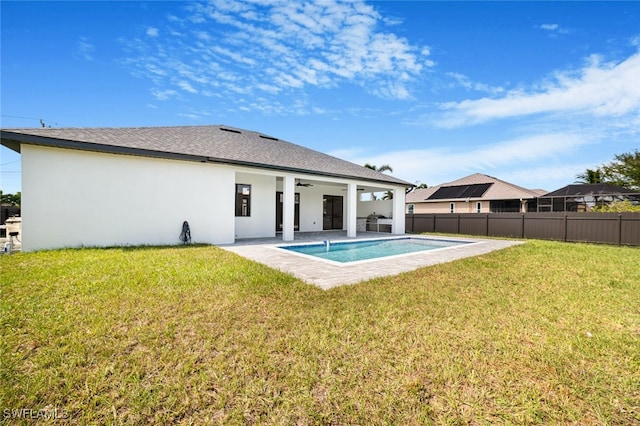 back of property with a yard, fence, a ceiling fan, and stucco siding