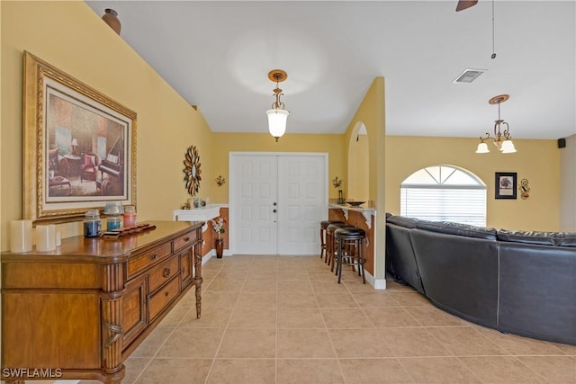 foyer featuring light tile patterned flooring, visible vents, baseboards, and ceiling fan with notable chandelier