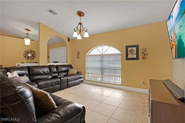 living area featuring arched walkways, a notable chandelier, light tile patterned floors, visible vents, and baseboards