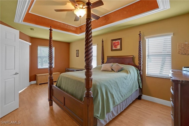 bedroom featuring light wood-style floors, multiple windows, and a raised ceiling