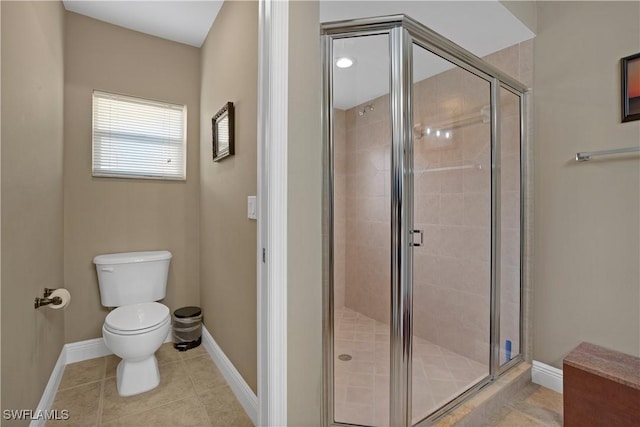 bathroom featuring a stall shower, toilet, and baseboards