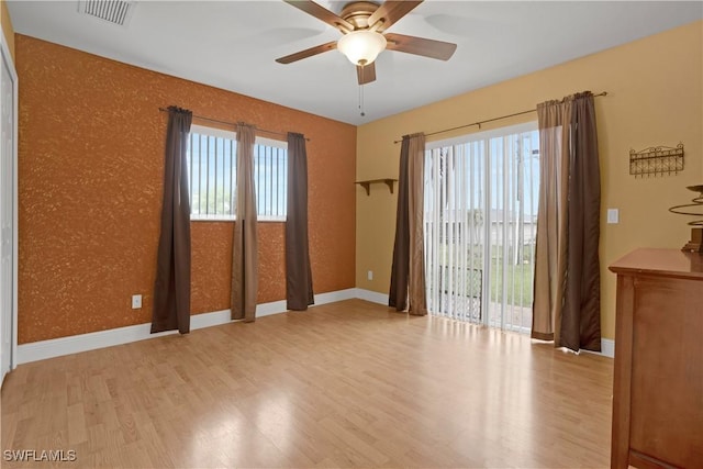 spare room featuring baseboards, visible vents, a wealth of natural light, and wood finished floors