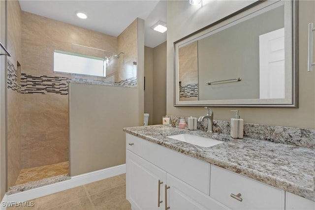 bathroom featuring a walk in shower, toilet, vanity, baseboards, and tile patterned floors