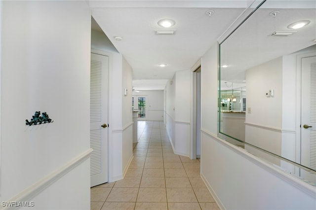 hall featuring light tile patterned flooring and baseboards