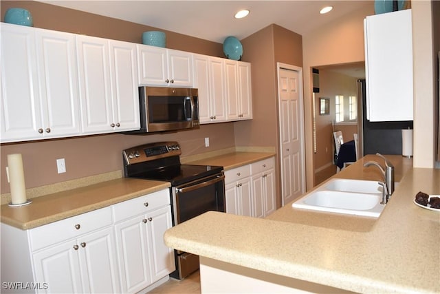 kitchen featuring stainless steel appliances, light countertops, white cabinets, and a sink