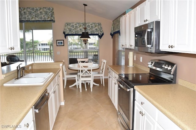 kitchen featuring white cabinets, appliances with stainless steel finishes, vaulted ceiling, light countertops, and a sink