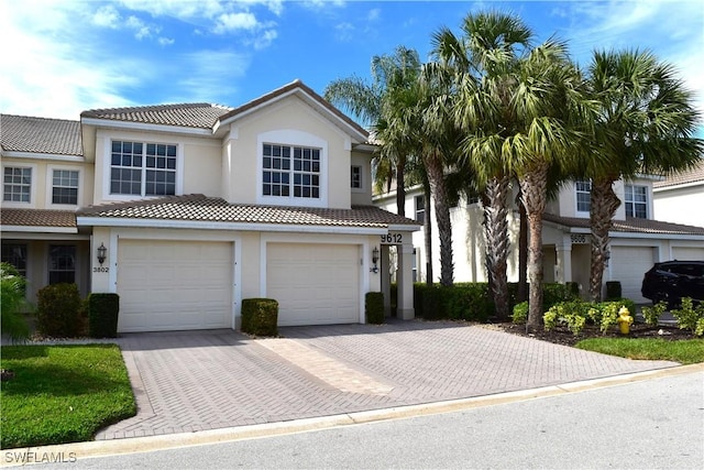 view of front of home with decorative driveway, an attached garage, and stucco siding