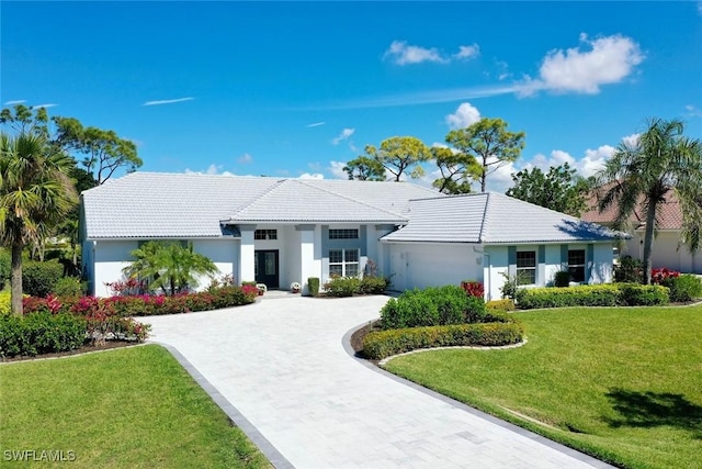 ranch-style home featuring stucco siding, a tiled roof, decorative driveway, and a front yard