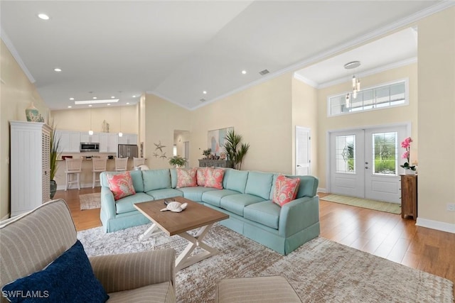 living room featuring crown molding, french doors, and light wood-style floors